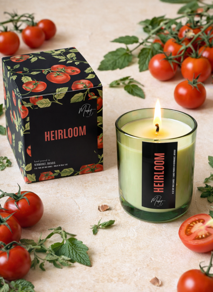 Heirloom tomato candle with packaging and tomatoes on a light surface